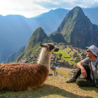 A man sitting with a llama in Machu Piccu, a UNESCO World Heritage Site in Peru. 
