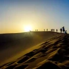 Hikers walking across a sand dune in Mongolia.