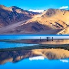 Trekkers enjoying the scenery and reflection of Pagong Tso Lake in Ladakh, India