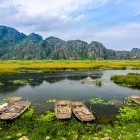 Traditional boats on the lake, with picturesque mountain scenery in th background, at Van Long Nature Reserve in Vietnam