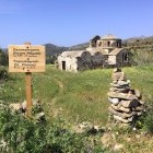 Waymarker, a pile of stones and a traditional building along a trail on Naxos Island, Greece