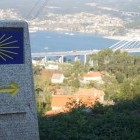 Way marker with Vigo in the background on the Camino de Santiago Coastal Way walking trail in Spain