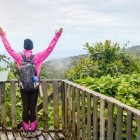 Female hiker raising her hands in the air over a viewpoint in a cloud forest, Costa Rica