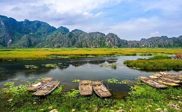 Traditional boats on the lake, with picturesque mountain scenery in th background, at Van Long Nature Reserve in Vietnam